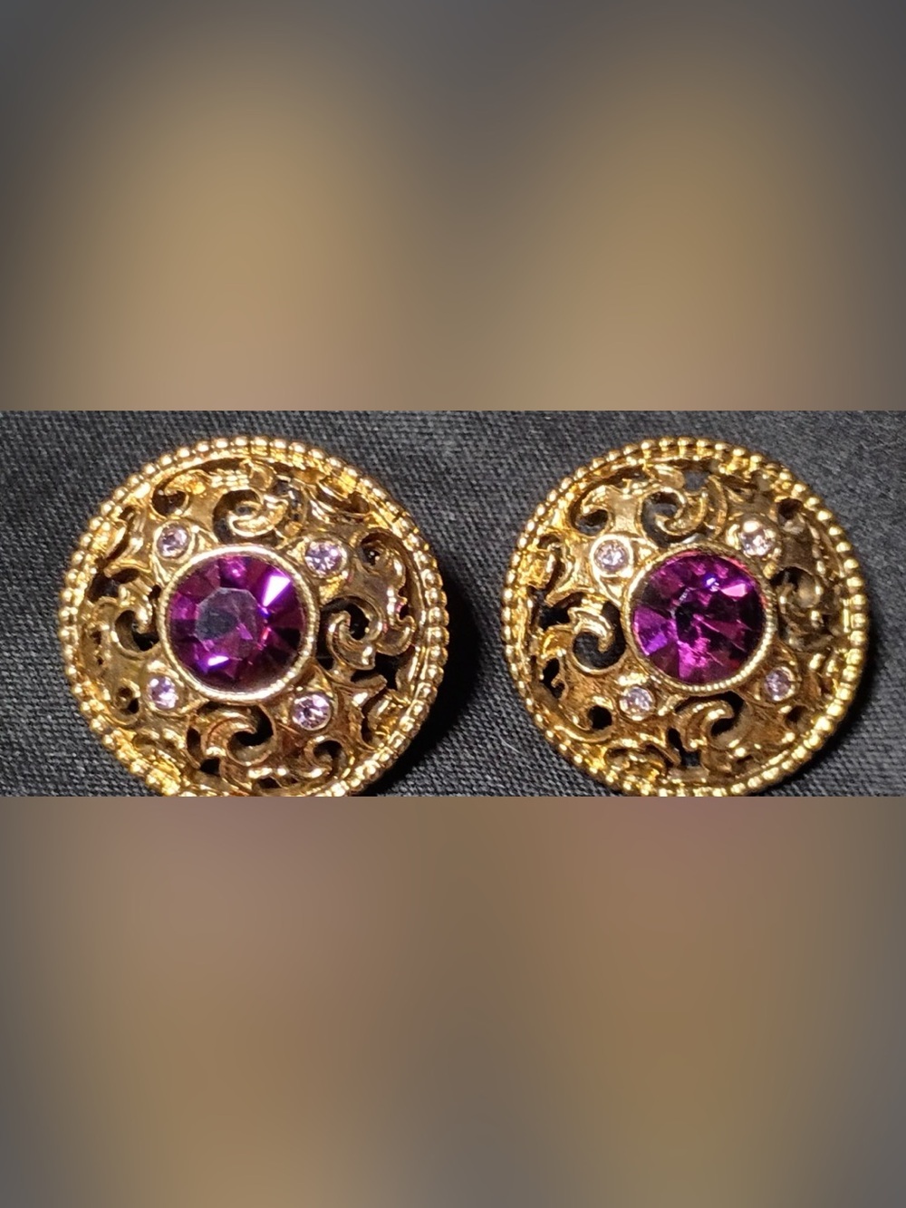 A vintage pair of gold plated filigree round earrings with purple rhinestones.